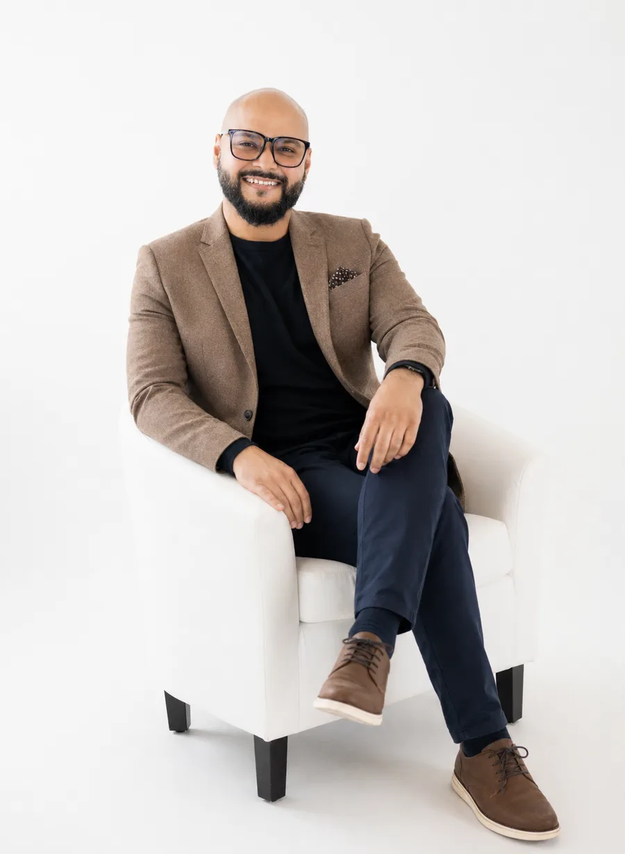 Dr. Laeeq Butt seated in a white armchair, smiling